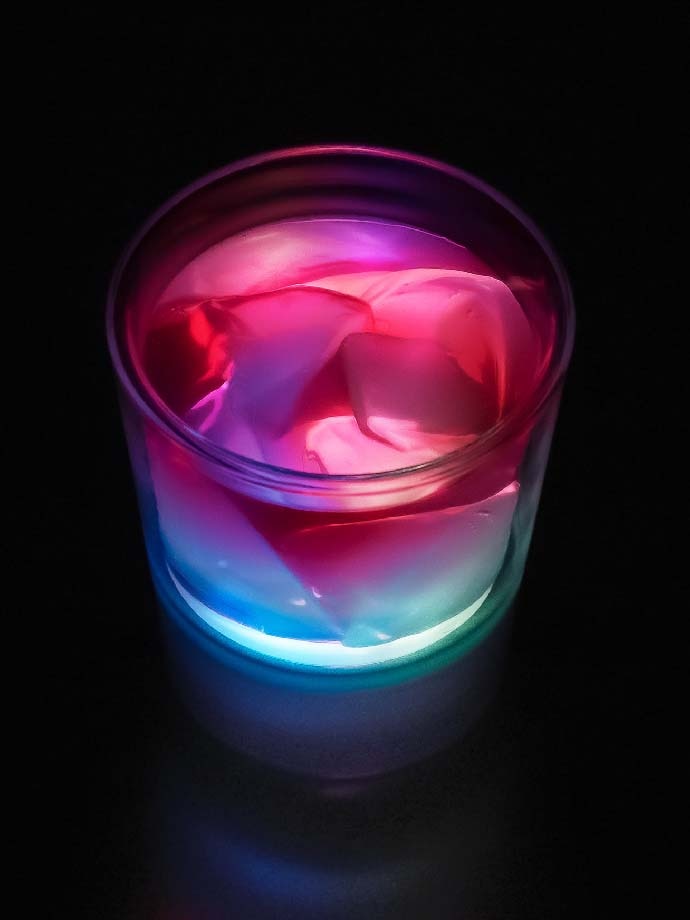 A glass of red and blue coloful tea