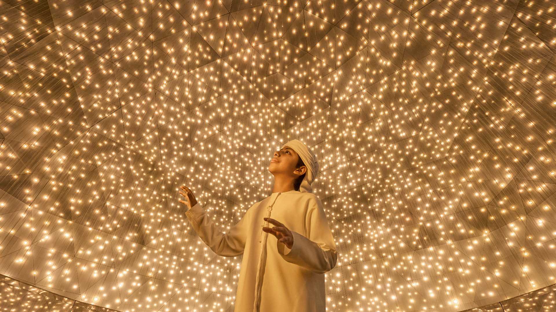 An arab teen staring up the ceiling looking at small light particles the look like little suns