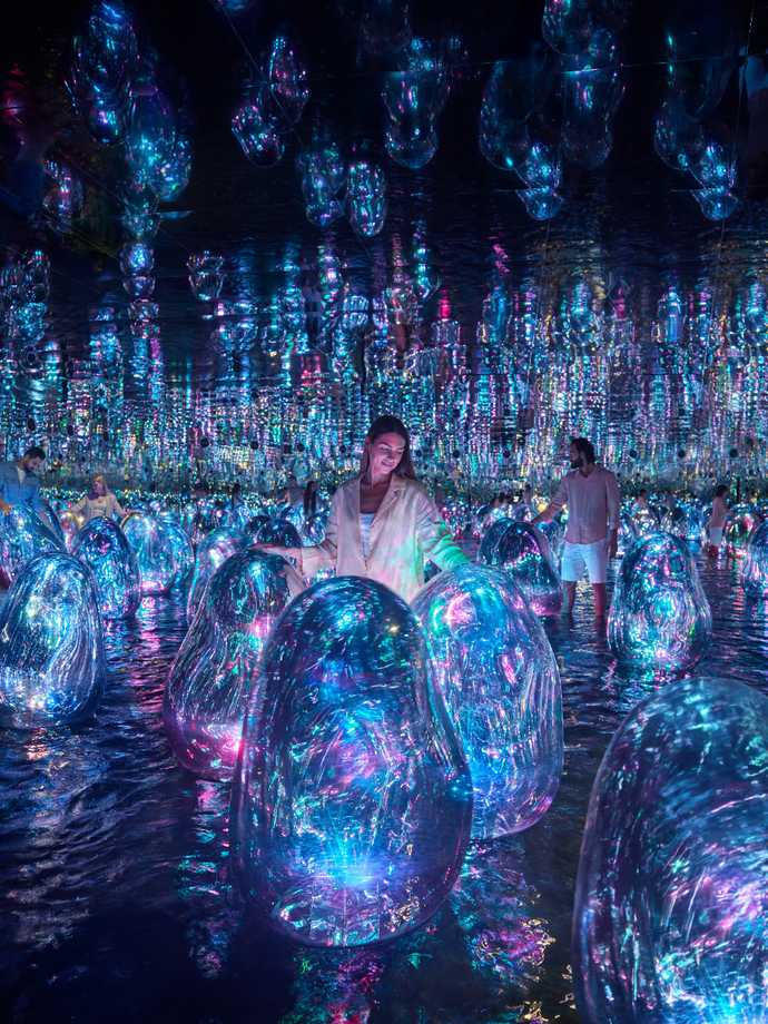 An asian lady dressed in white interacting with a floating egg looking artwork called Floating Microcosms.